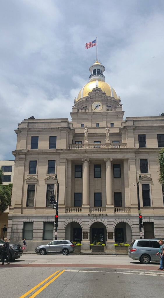 Savannah City Hall in Georgia, showing its clock tower and gold dome above the street.